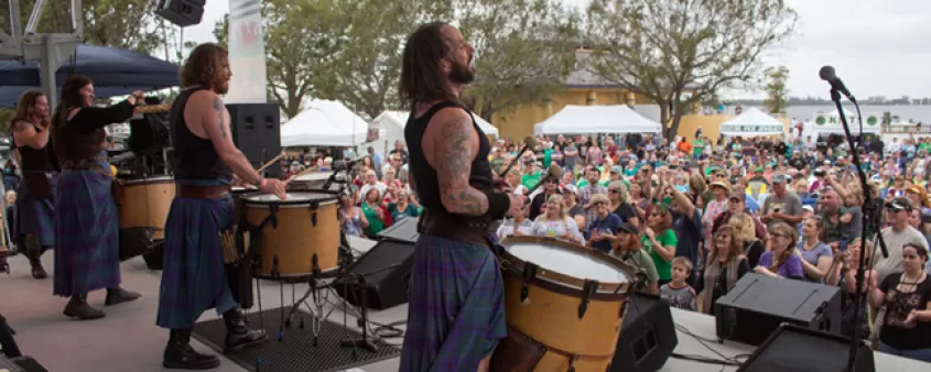 Performers on stage looking out at audience in chairs on lawn
